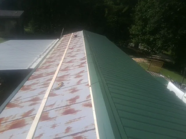Old rusted panels beside newly installed green metal roofing — Wind Damage Roof Repair by Roofing Brothers in Victorville