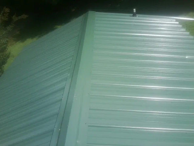 New green metal panels meeting at the ridge of a roof — Flat Roof Repair work by our crew in Victorville