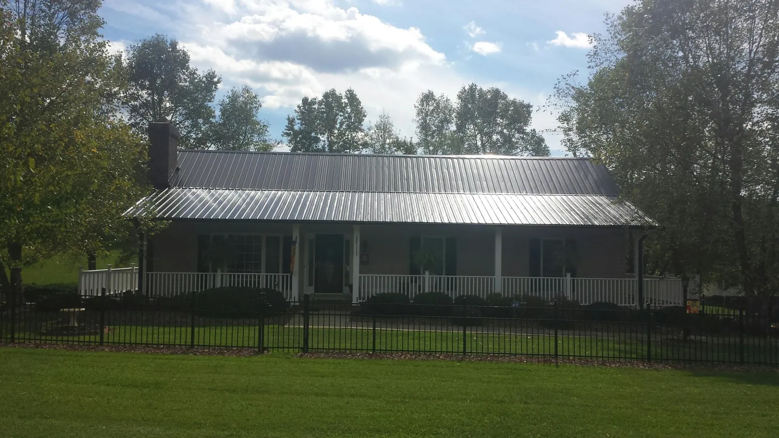 Gray metal roof on a brick ranch with a full width front porch — Gutter Guard Installation work by our crew in Victorville