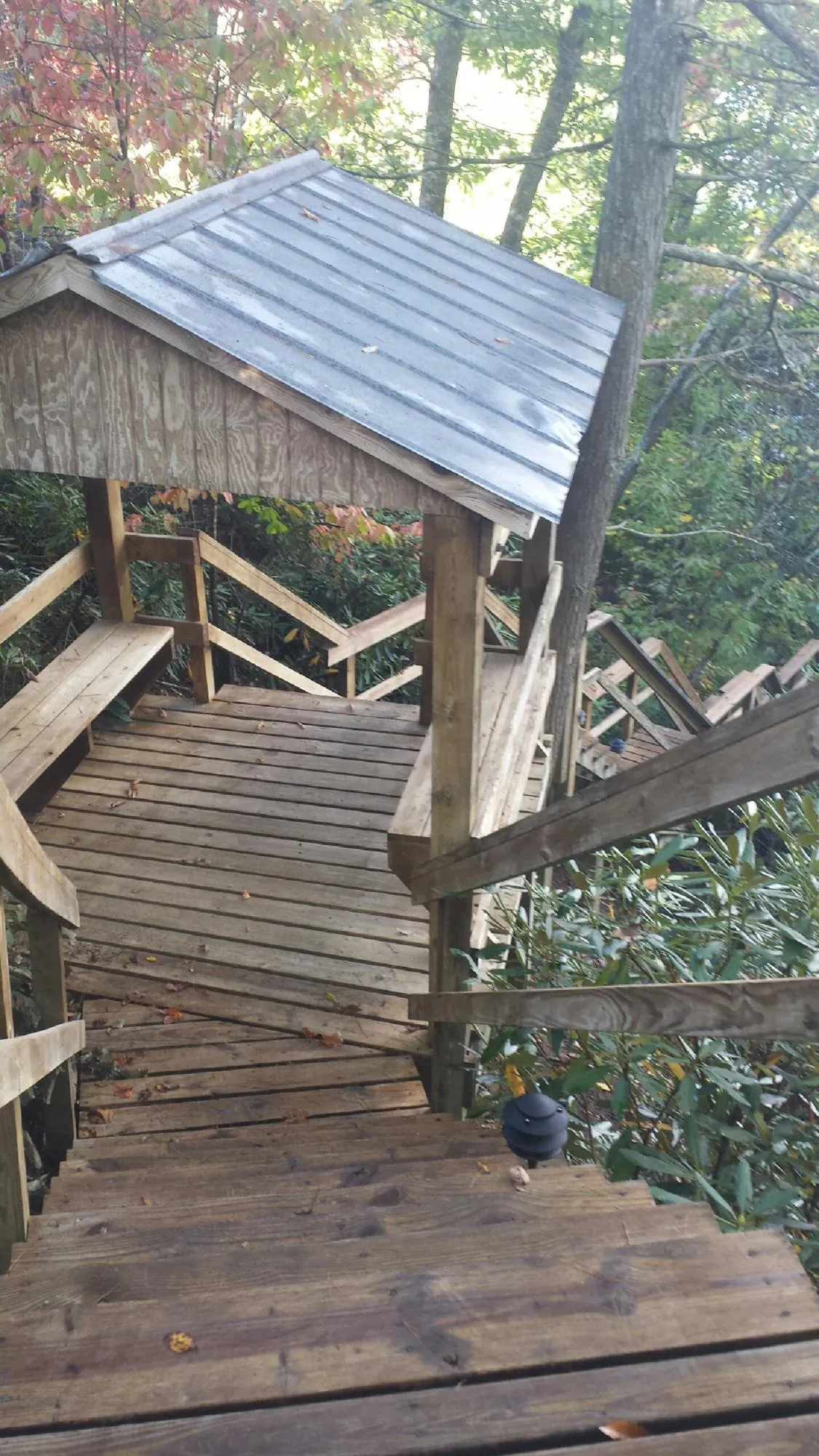 Metal roofed shelter over wooden steps on a wooded walkway — Skylight Repair & Installation work by our crew in Victorville