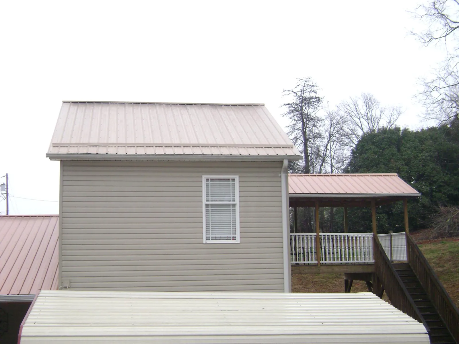 Tan metal roofs on a two story addition and attached porch, from a Roof Replacement job in Victorville