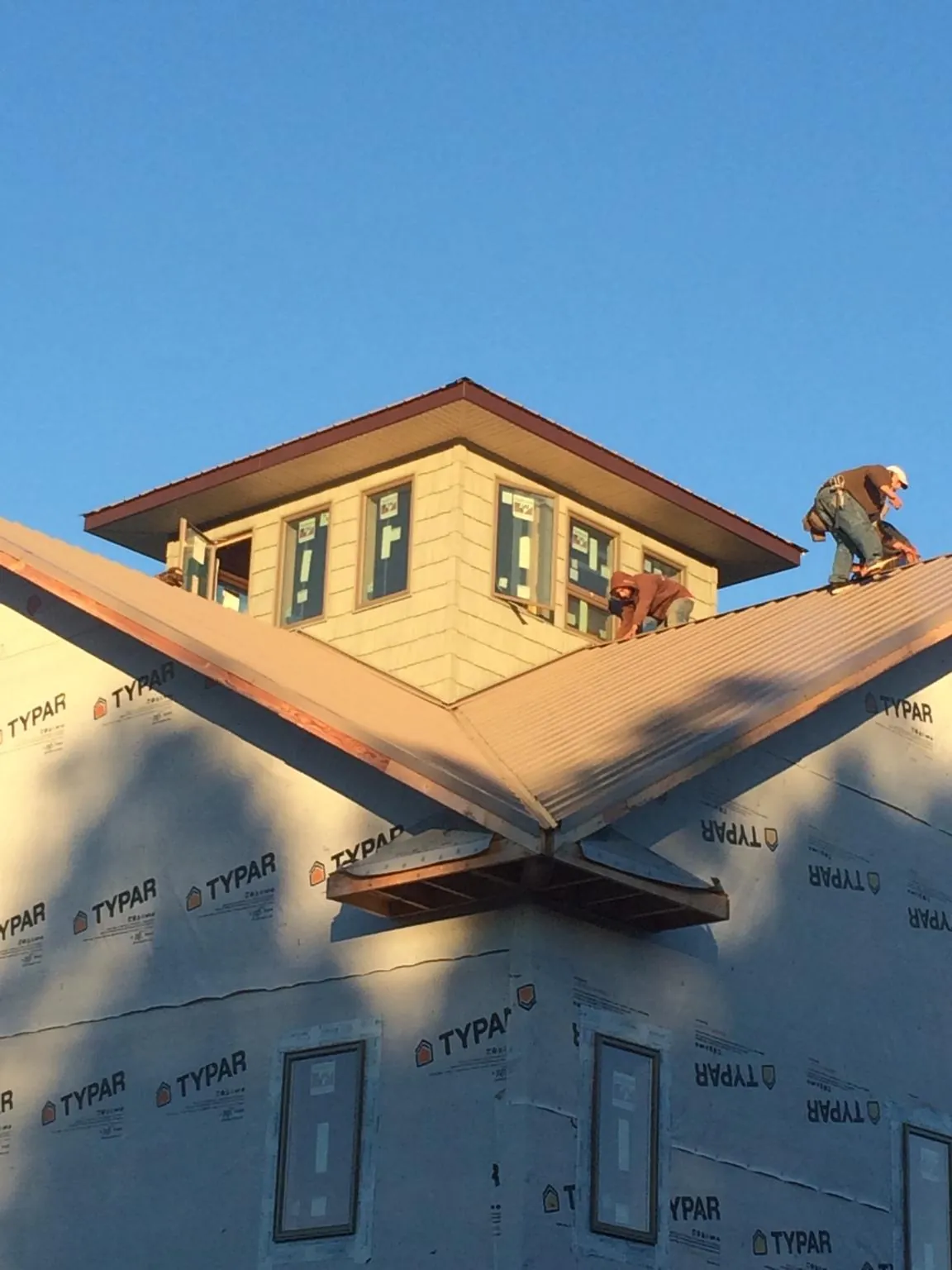 Roofers working around a rooftop cupola on a new metal roof at sunset — Roof Waterproofing in Victorville by Roofing Brothers